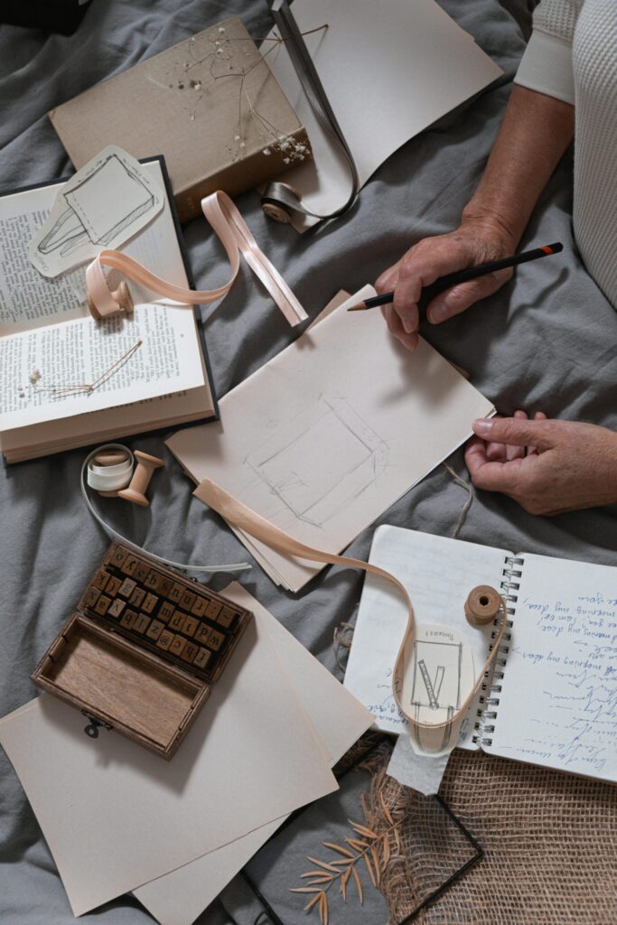 Overhead view of a creative workspace with sketching materials and stationery on gray fabric.